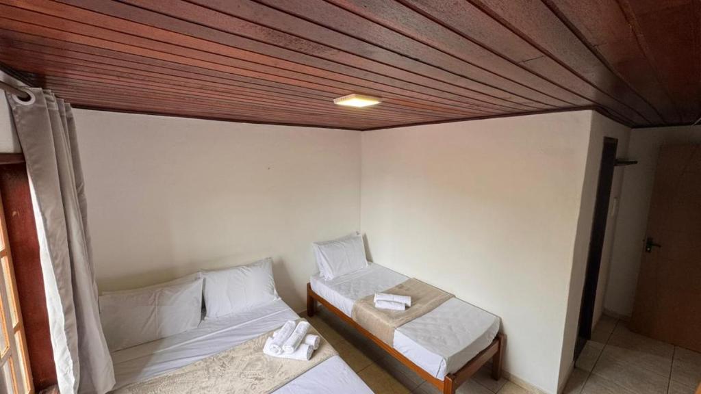 a bedroom with two beds and a wooden ceiling at GO Hotelaria in Búzios
