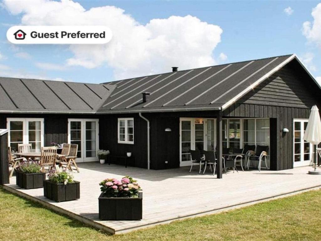 een huis met een zwart dak en een terras bij 10 person holiday home in Nysted-By Traum in Nysted
