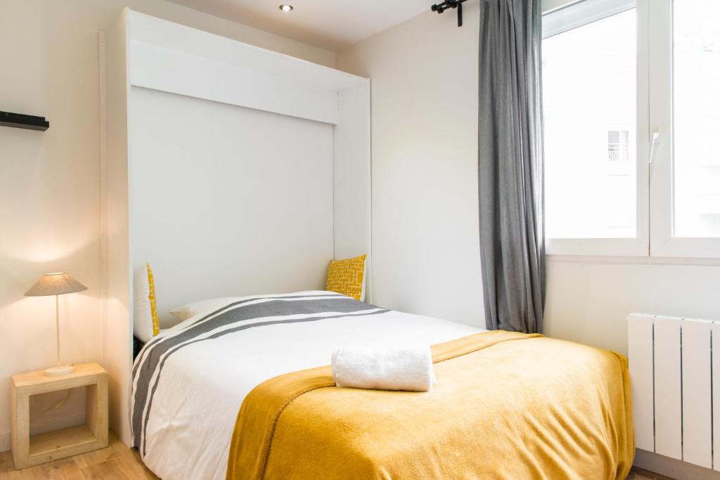 a bedroom with a bed with a yellow blanket at Unsejouranantes - Le Magellan in Nantes