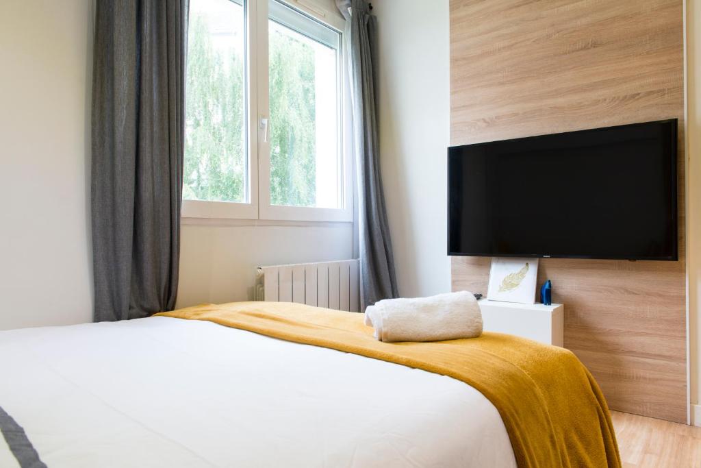 a bedroom with a large bed and a flat screen tv at Unsejouranantes - Le Magellan in Nantes