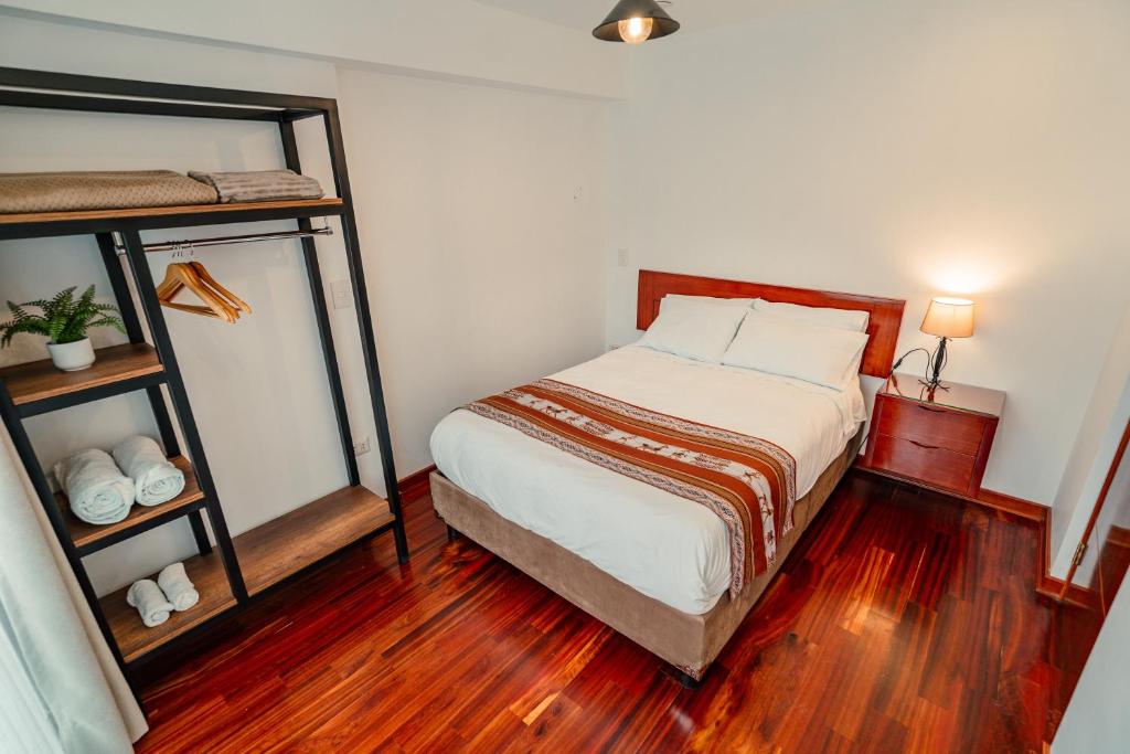 een slaapkamer met een bed en een houten vloer bij Apartamento con todo cerca en Cusco in Cuzco
