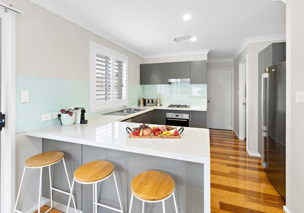 a kitchen with a white counter and two stools at Haus on Moore in Oak Flats