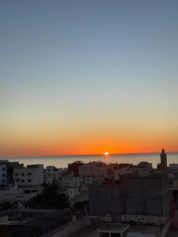 Una puesta de sol sobre una ciudad con el océano en Lumir Surf House, en Tamraght Ouzdar