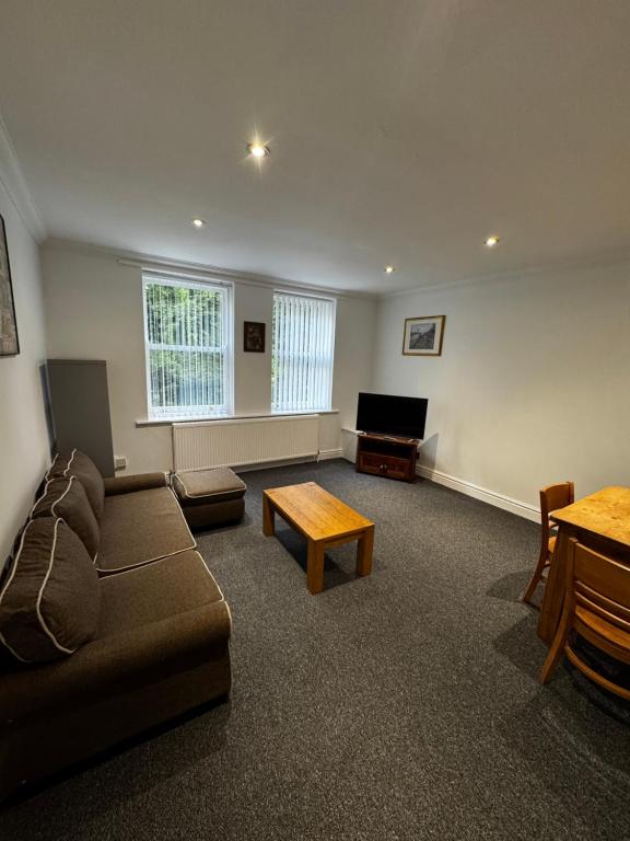 a living room with a couch and a flat screen tv at No 4 AT SANDRINGHAM - LARGE 2 BED NEAR SEFTON PARK in Liverpool