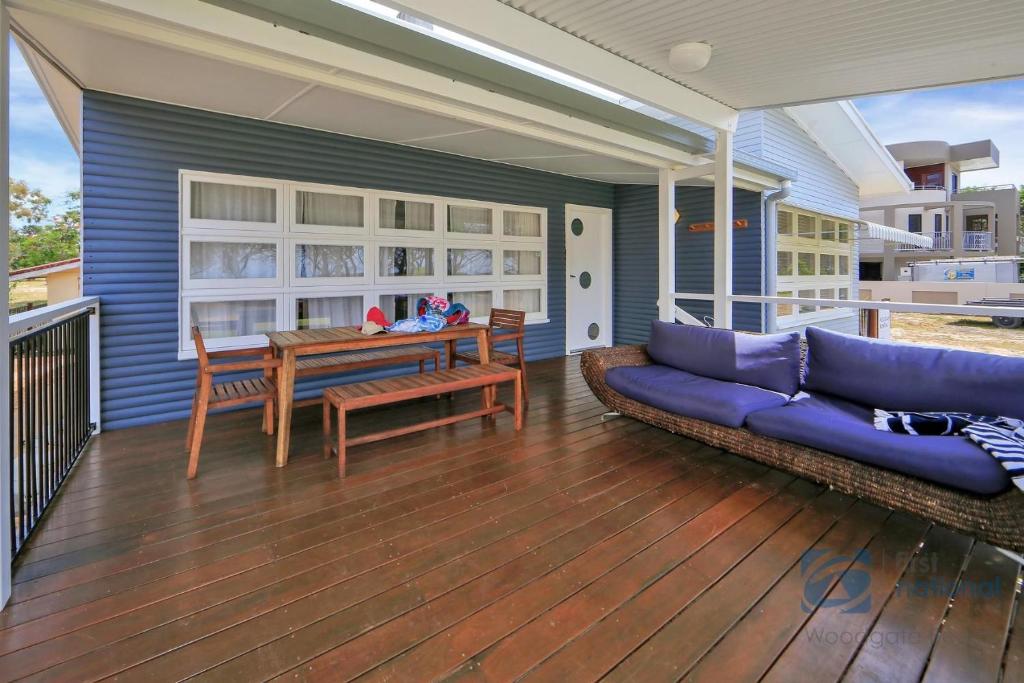 a patio with a couch and a table on a deck at 1 The Esplanade in Woodgate