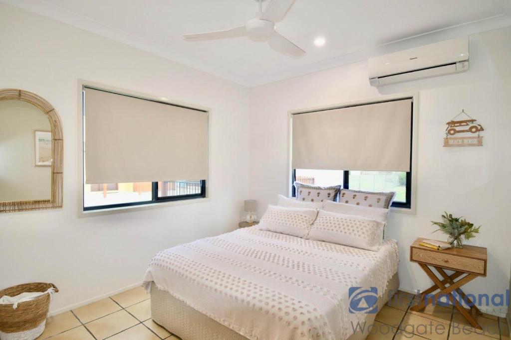 a bedroom with a white bed and two windows at 2/84 The Esplanade in Woodgate