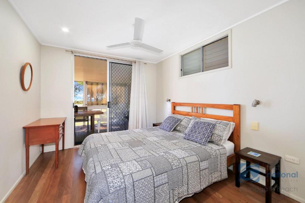a bedroom with a bed and a table and a desk at 185 The Esplanade in Woodgate