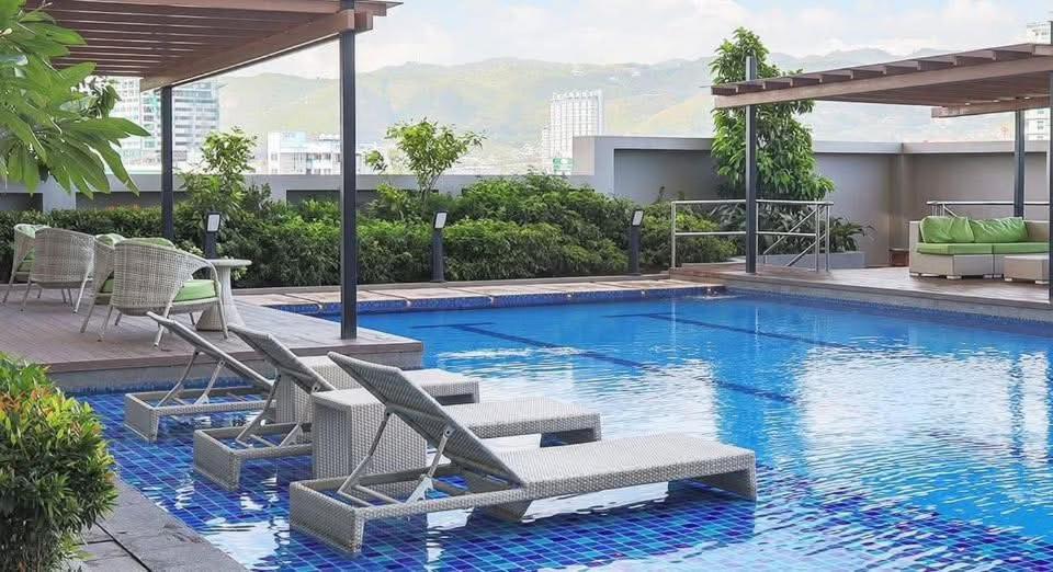 a swimming pool with chaise lounge chairs next to a building at Horizons 101 in Cebu City