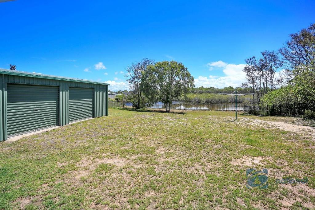 an open yard with a green building and a pond at 198 The Esplanade in Woodgate