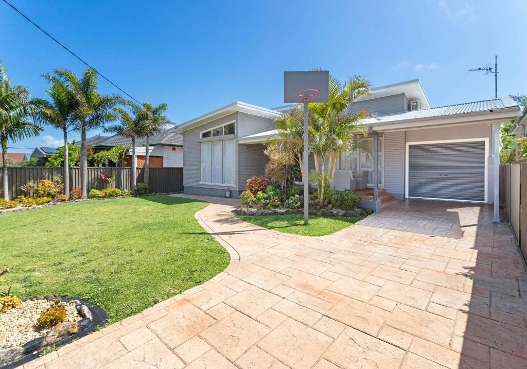 a house with a driveway in front of a yard at Coastal Palms - Family & Pet-Friendly Beachside Haven in Lake Illawarra