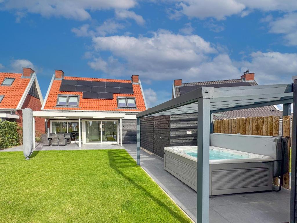 Un patio trasero con piscina y una casa. en Coast and Calm 63, en Colijnsplaat