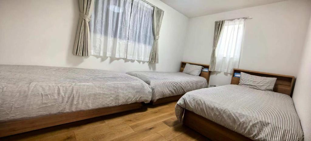een slaapkamer met twee bedden en een raam bij Kamakura Koshigoe Ekimae B in Kamakura