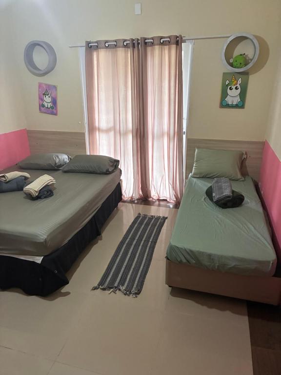 two beds sitting in a room with a window at pousada ranchinho sorocaba in Sorocaba