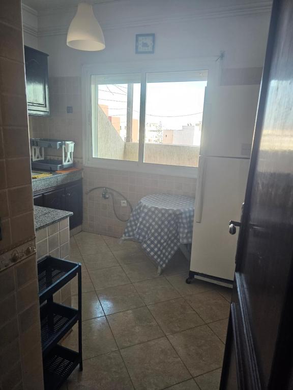 a kitchen with a white refrigerator and a window at Appartement famille plage in El Jadida