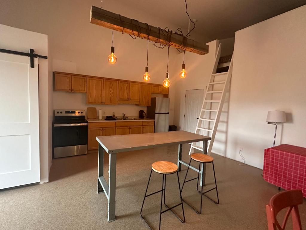 a kitchen with a table and two stools and a ladder at Mezzanine Loft Above the Barn in Whitehorse