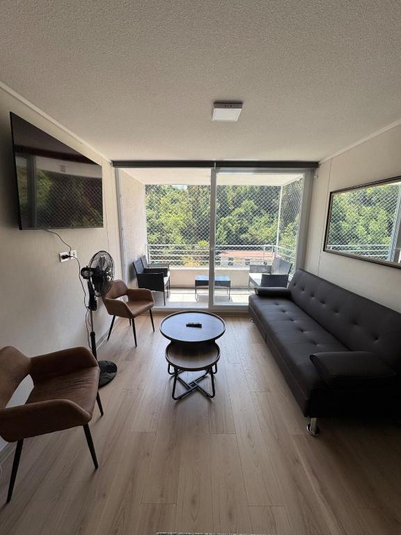 een woonkamer met een zwarte bank en een tafel bij Departamento nuevo 2D-2B 5 Pasajeros in Viña del Mar