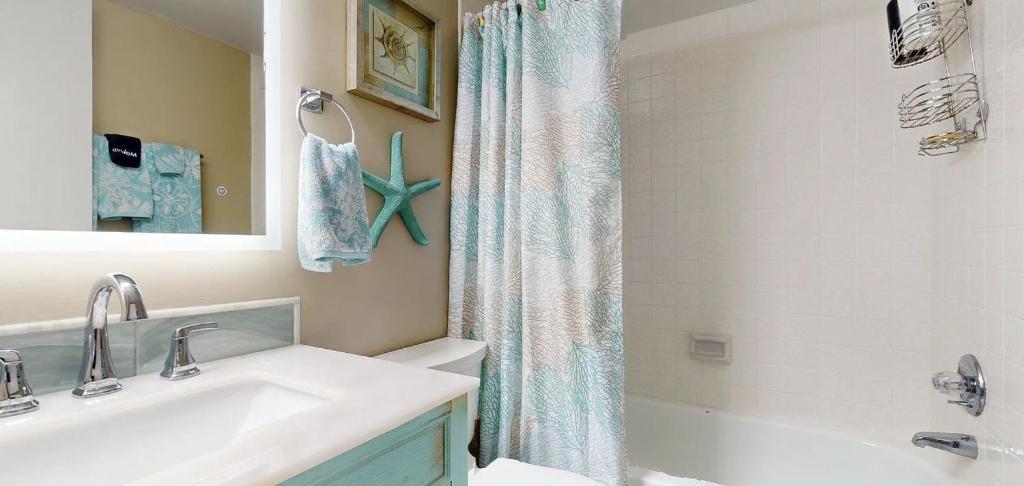 a bathroom with a sink and a shower curtain at Beachfront Space Coast Gem with Heated Pool, Sleeps 4 in Cape Canaveral