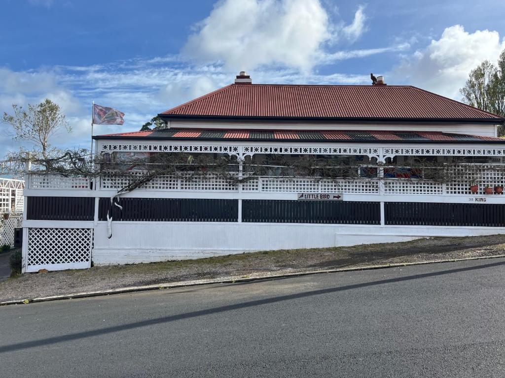 a white building with a red roof on the side of a street at Little bird in Smithton