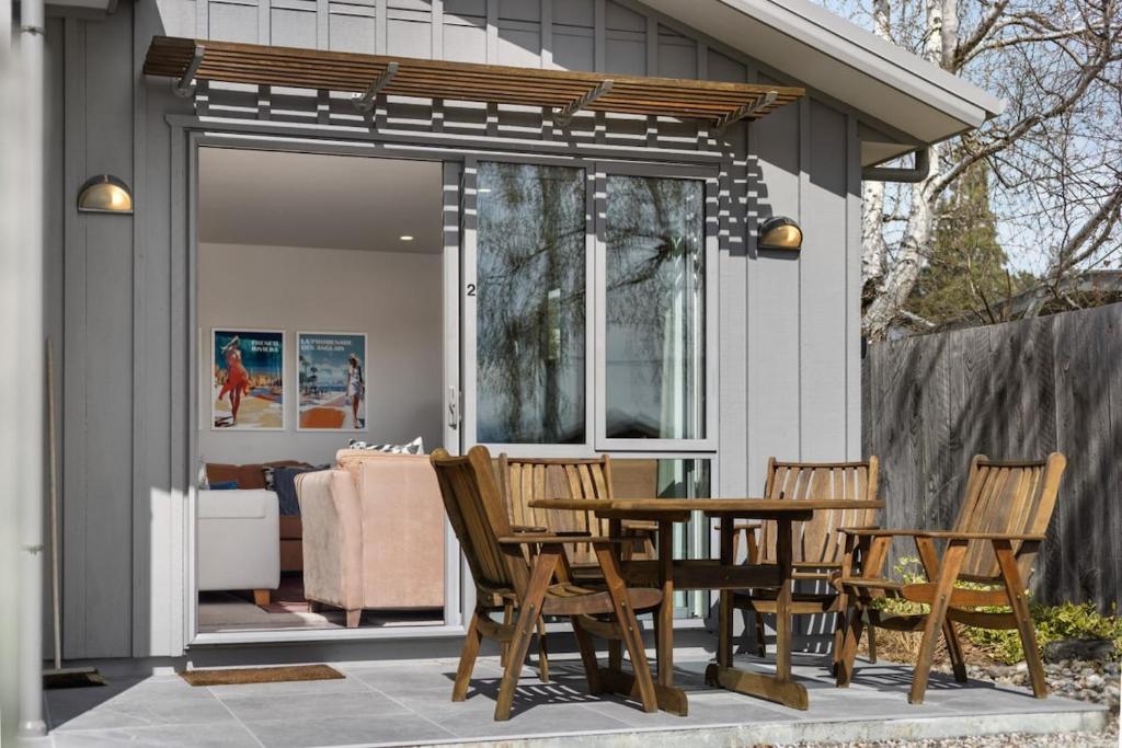 eine Terrasse mit Stühlen, einem Tisch und einem Haus in der Unterkunft Amazing Location! Central 2 bedroom Unit in Wanaka
