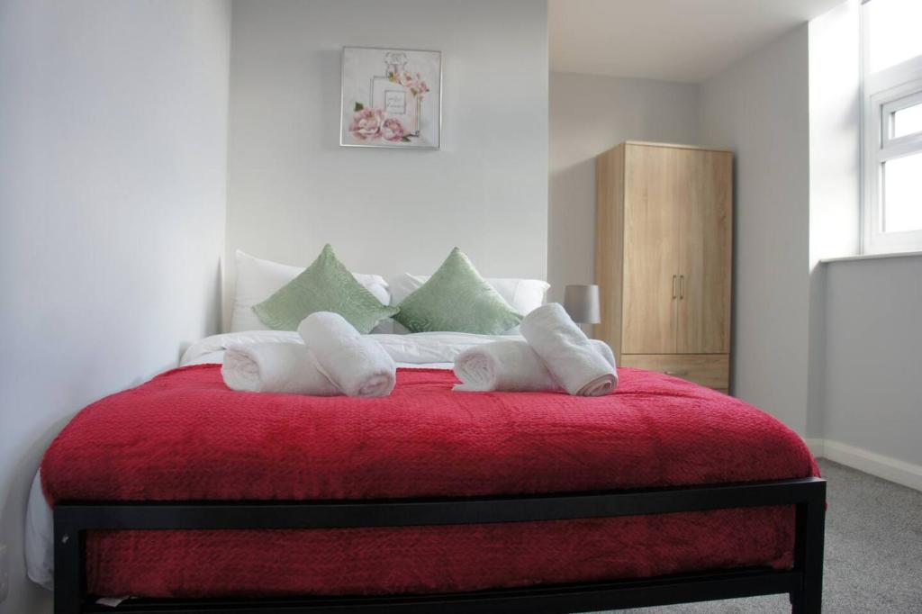 une chambre avec un lit rouge avec des serviettes dessus dans l'établissement Melbourne House Gem Stylish 2-bed In City Centre, à Accrington