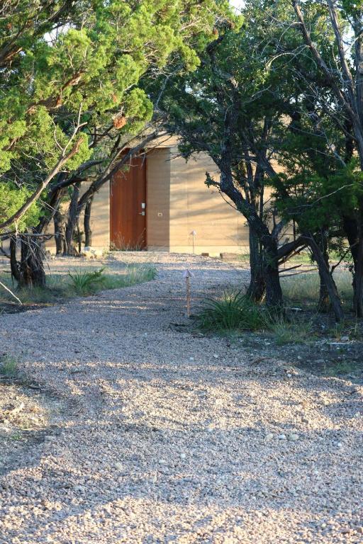 a building with a red door next to some trees at Red-tail Cabin at Gamenthaler in Fredericksburg