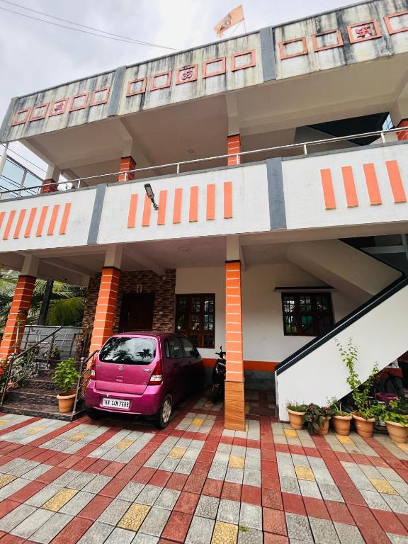 une voiture rose garée devant un bâtiment dans l'établissement Manikya Homestay, à Malpe
