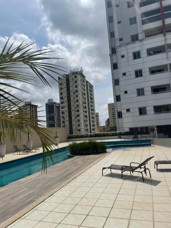 a pool with two benches and some buildings at Apt 3 quartos com área de lazer in Belém