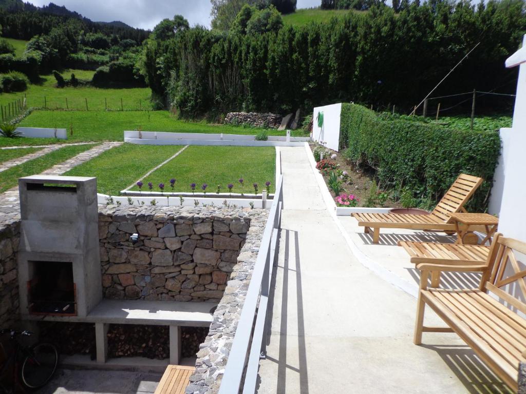 a patio with two benches and a stone wall at Casa do Simão in Nordeste