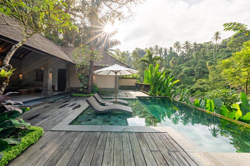 an outdoor pool with an umbrella and a chair at The Lokha Ubud Resort, Villas & SPA in Ubud