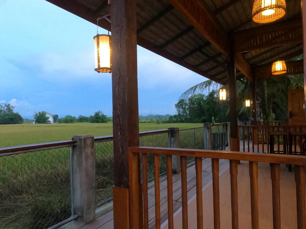 een veranda van een restaurant met uitzicht op een veld bij สมายด์ ฮ่อมนา เรสเฮาท์ Smile Homna Resthouse in Ban Mae Chong