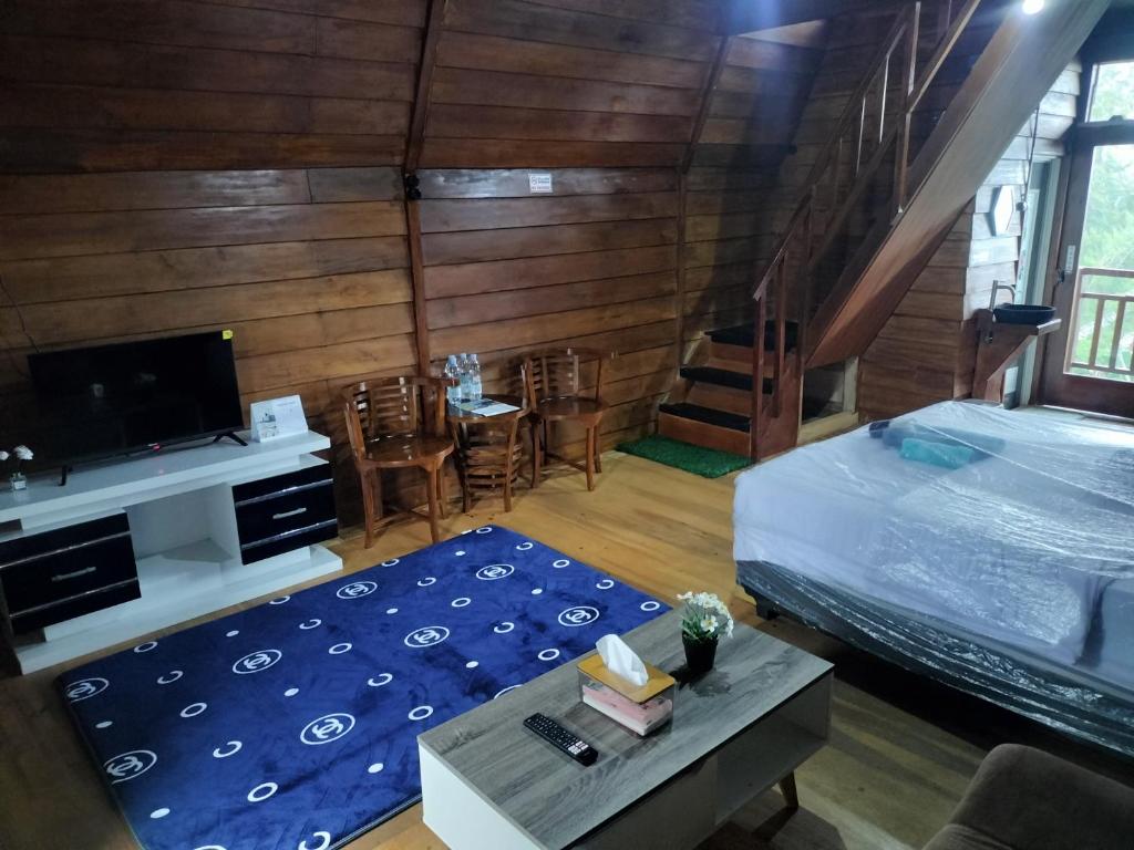 a bedroom with a bed and a tv and a table at The Aisyah Cabin in Wonosobo