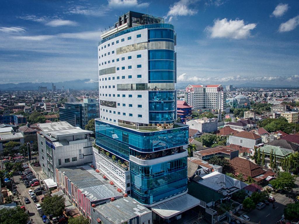 a tall blue and white building in a city at Melia Makassar in Makassar