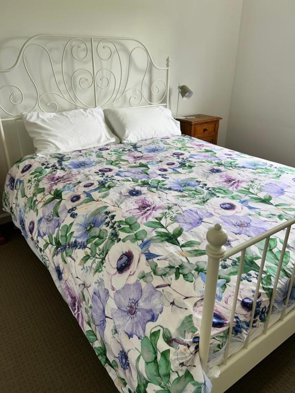 a bed with a floral comforter on it at Grandad's farmhouse in Northcliffe