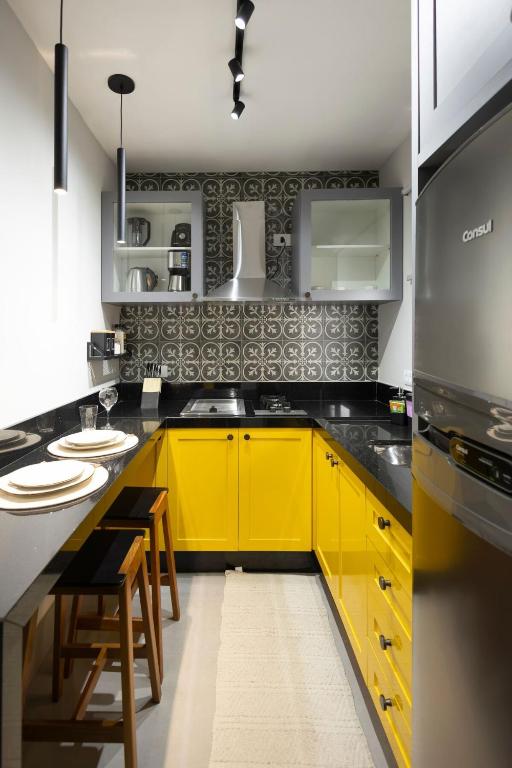 a kitchen with yellow cabinets and a yellow island in it at 113-Studio Amplo e completo com ar condicionado prox UEL in Londrina