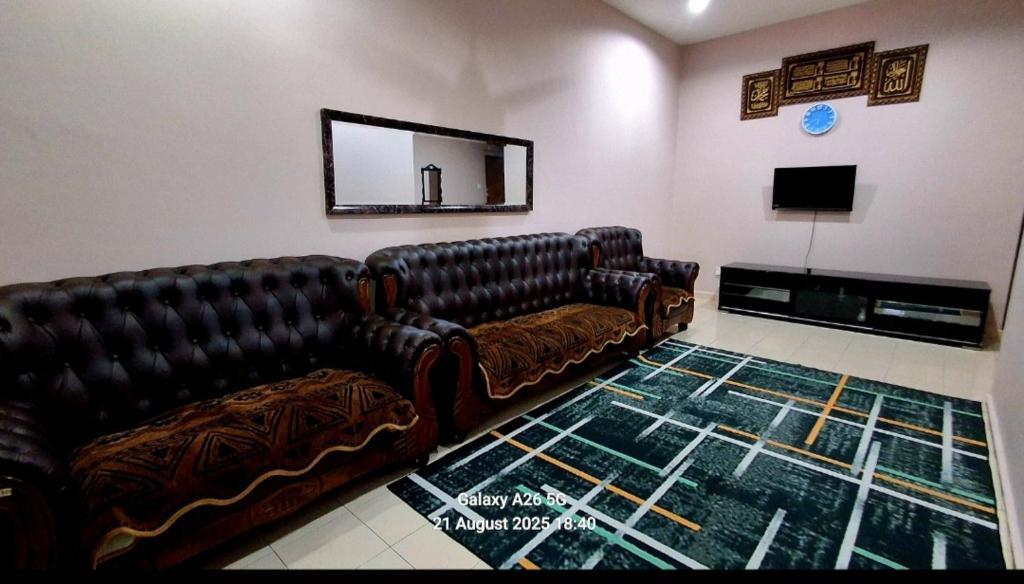 a living room with two leather couches and a fireplace at Homestay Kuala Berang Solehah Full Aircond Wifi & Netflix in Kuala Berang