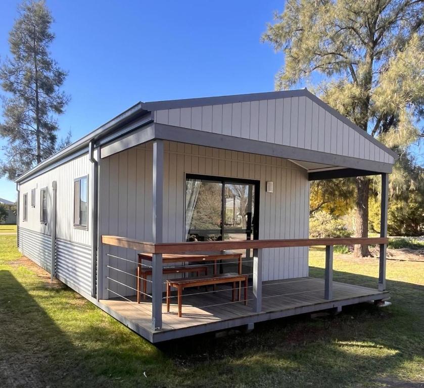a tiny house with a porch and a bench at Griffith Caravan Village in Yoogali