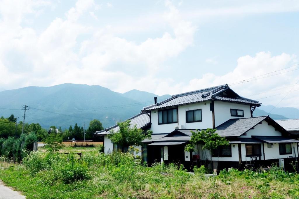 a house on a hill with mountains in the background at 安曇野ふくろうハウス The OWL Villa mountain view in Hotaka