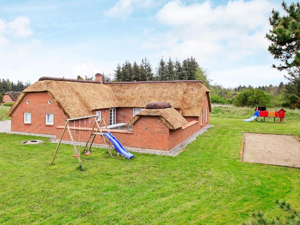 a house with a thatched roof with a playground at Luxury Retreat near Beach - By Traum Ferienwohnungen in Husby