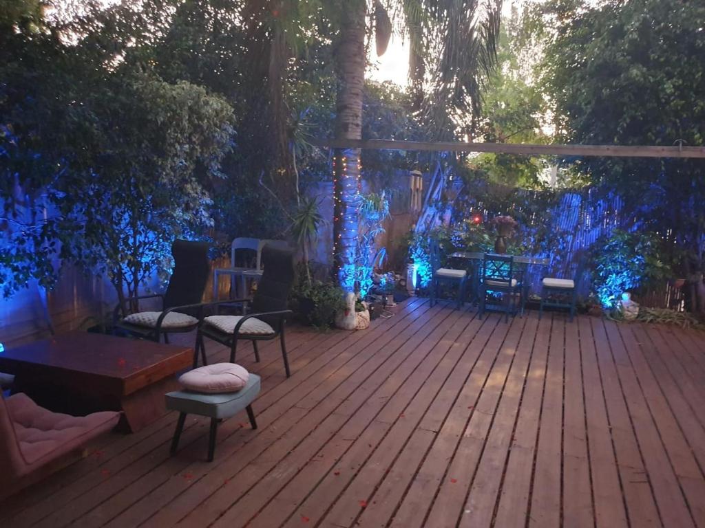 a deck with blue lights and chairs and trees at Happy Place in Tel Aviv
