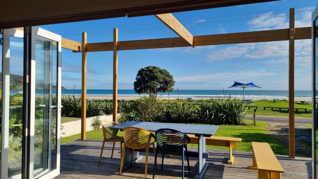 eine Terrasse mit einem Tisch und Stühlen sowie Strandblick in der Unterkunft Beach Break in Ahipara