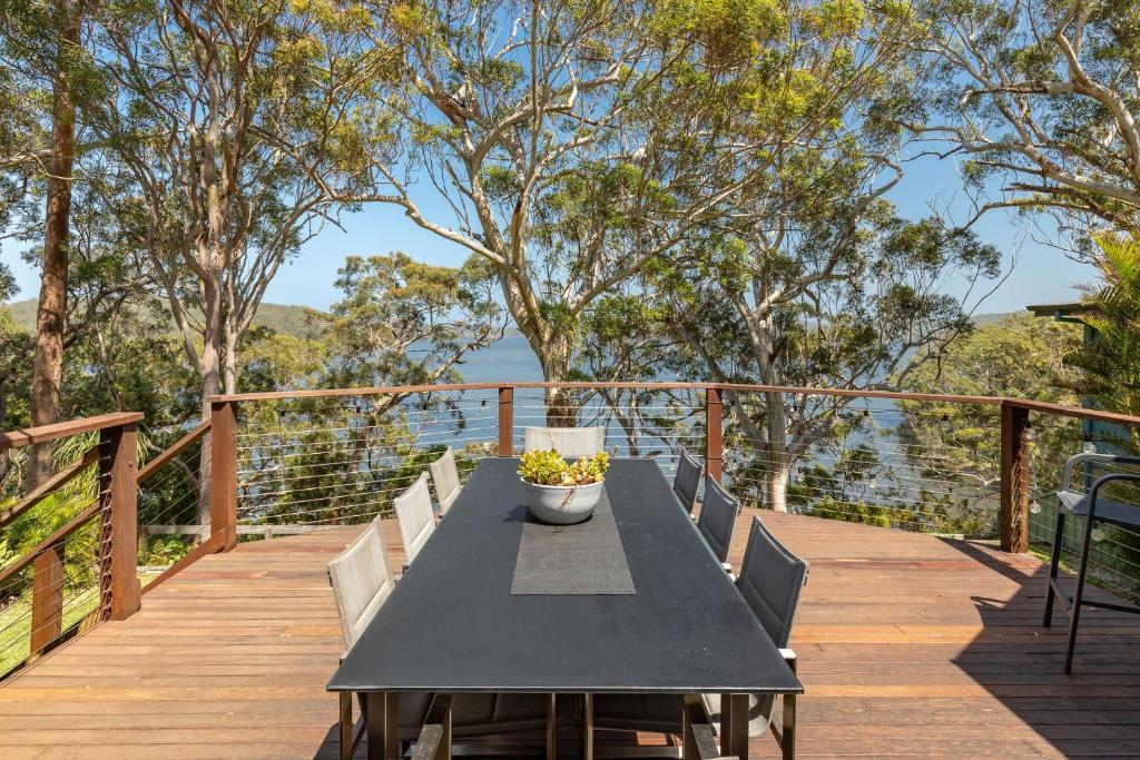 a black table and chairs on a wooden deck at Luminara Luxury Lakefront in Smiths Lake