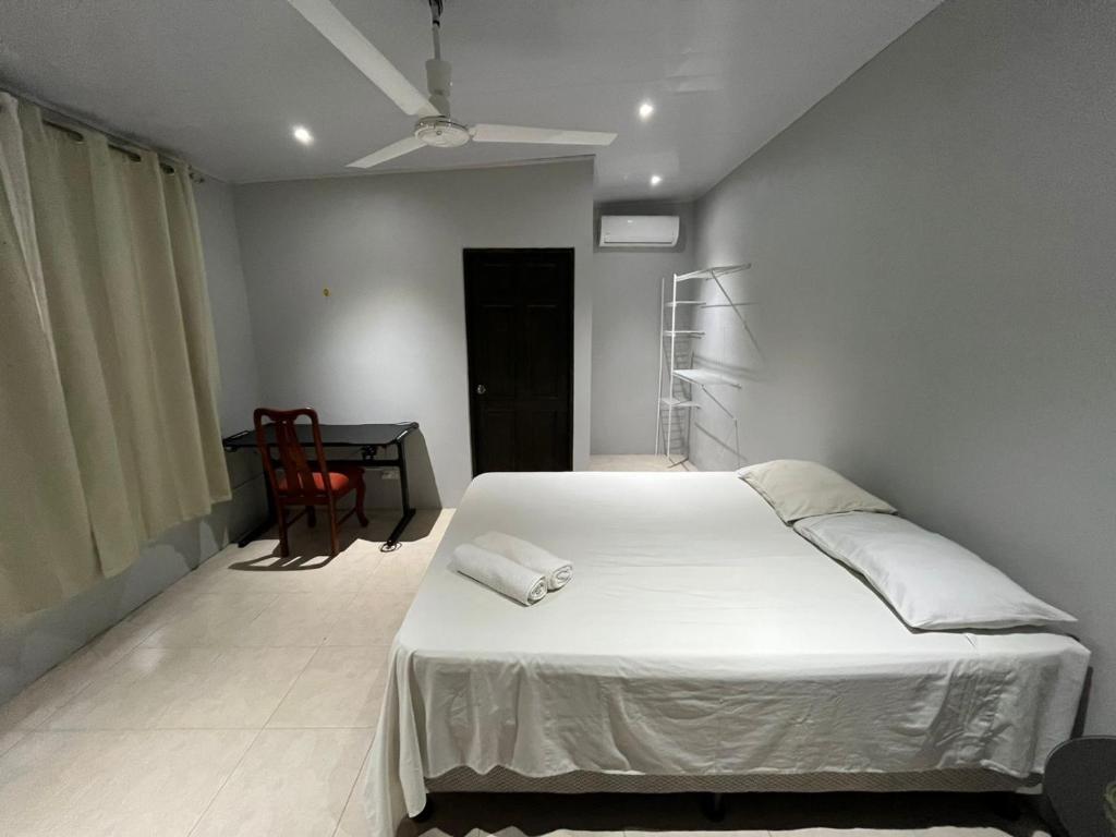 a bedroom with a white bed and a desk at Casa playa in Huacas