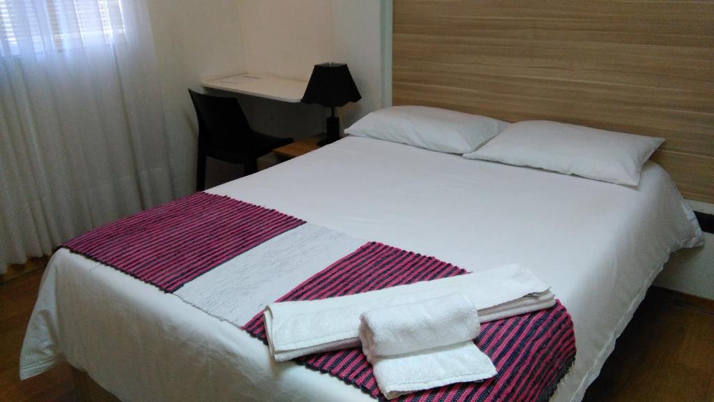 a bedroom with a white bed with towels on it at Acosta Ñu Apart Hotel in Asunción