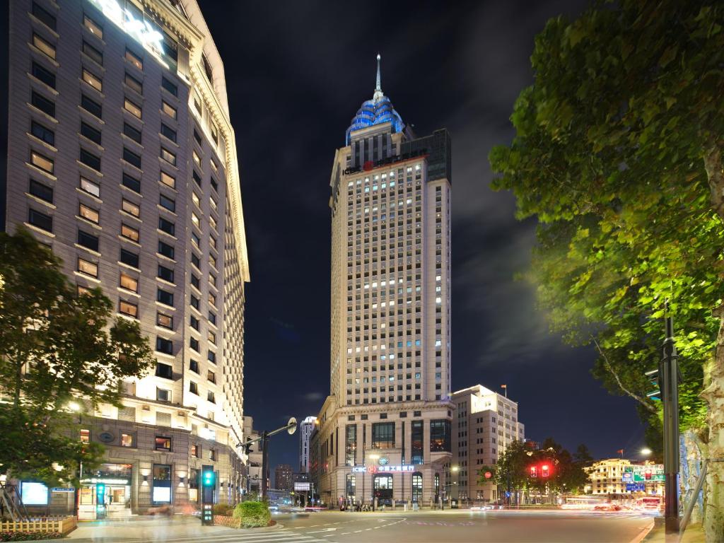 een hoog gebouw met 's nachts een blauwe koepel bij Jinglai Hotel Bushe - Shanghai Nanjing East Road Bund Branch in Shanghai