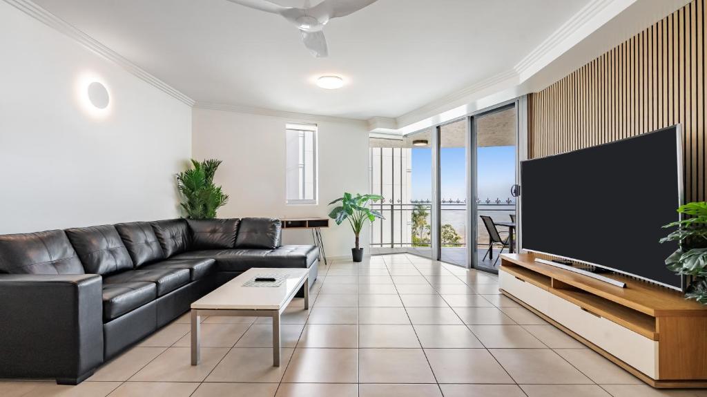 a living room with a black leather couch and a flat screen tv at Ocean View 3-Bedroom Apartment on the Esplanade in Cairns