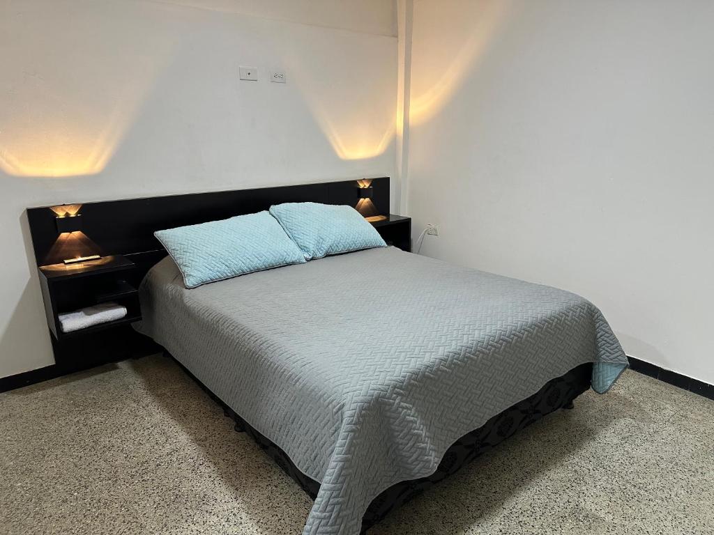 a bedroom with a bed with a blue pillow on it at Apartamentos FM 204 in Líbano