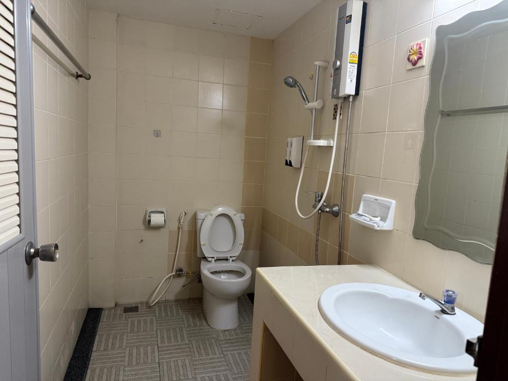 A compact tiled bathroom with a toilet, vanity sink and handheld shower.