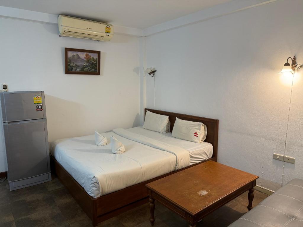 A compact bedroom pairs a double bed with a sofa, coffee table and full-height refrigerator.