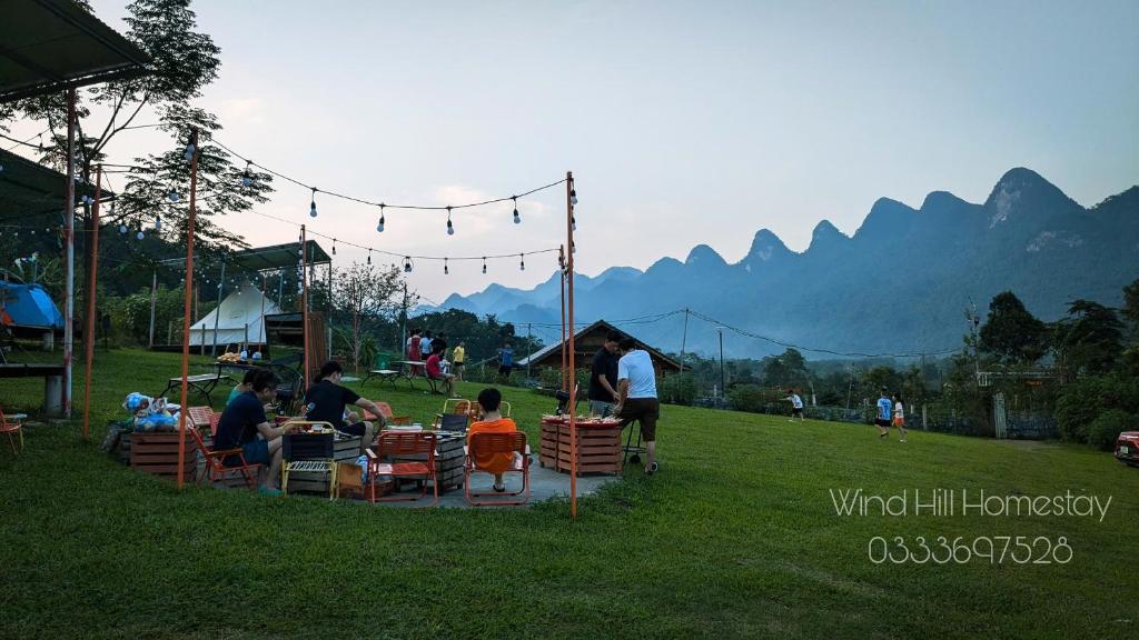 Un grupo de personas sentadas en mesas en el césped. en Đồi Gió Homestay & Campsite, en Ha Giang