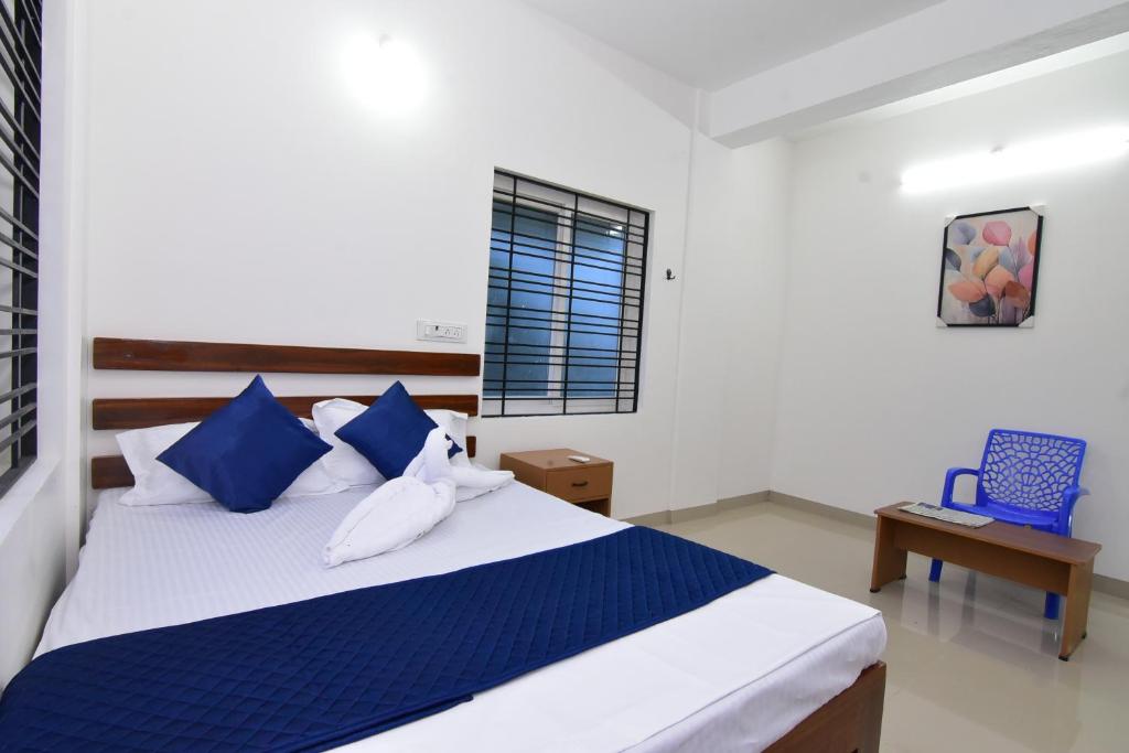 a bedroom with a bed with blue and white pillows at Pondicherry Comfort Rooms in Puducherry